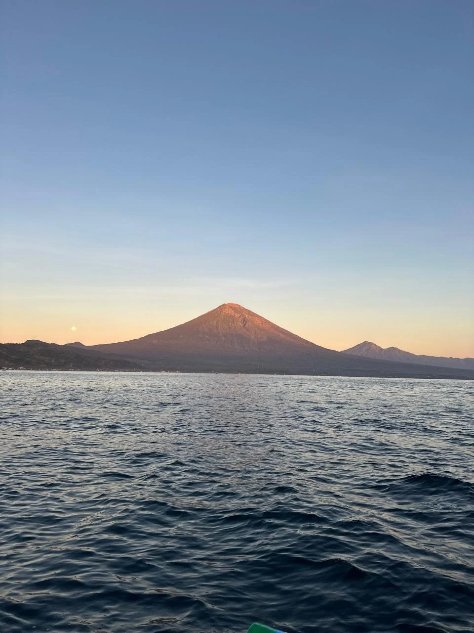Mount Agung glowing at dawn seen from the sea off Amed