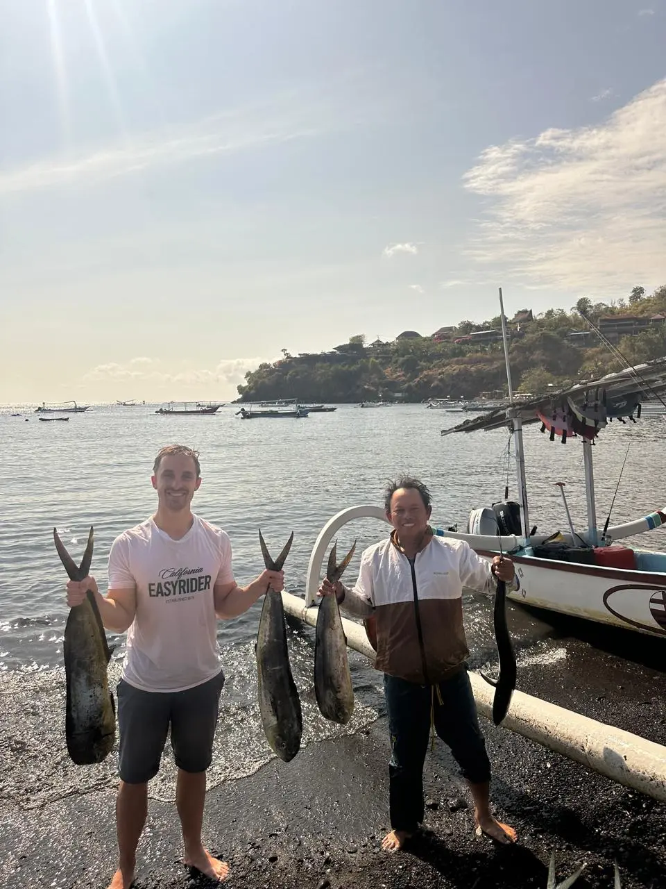 Anglers holding their catch on the volcanic beach of Amed