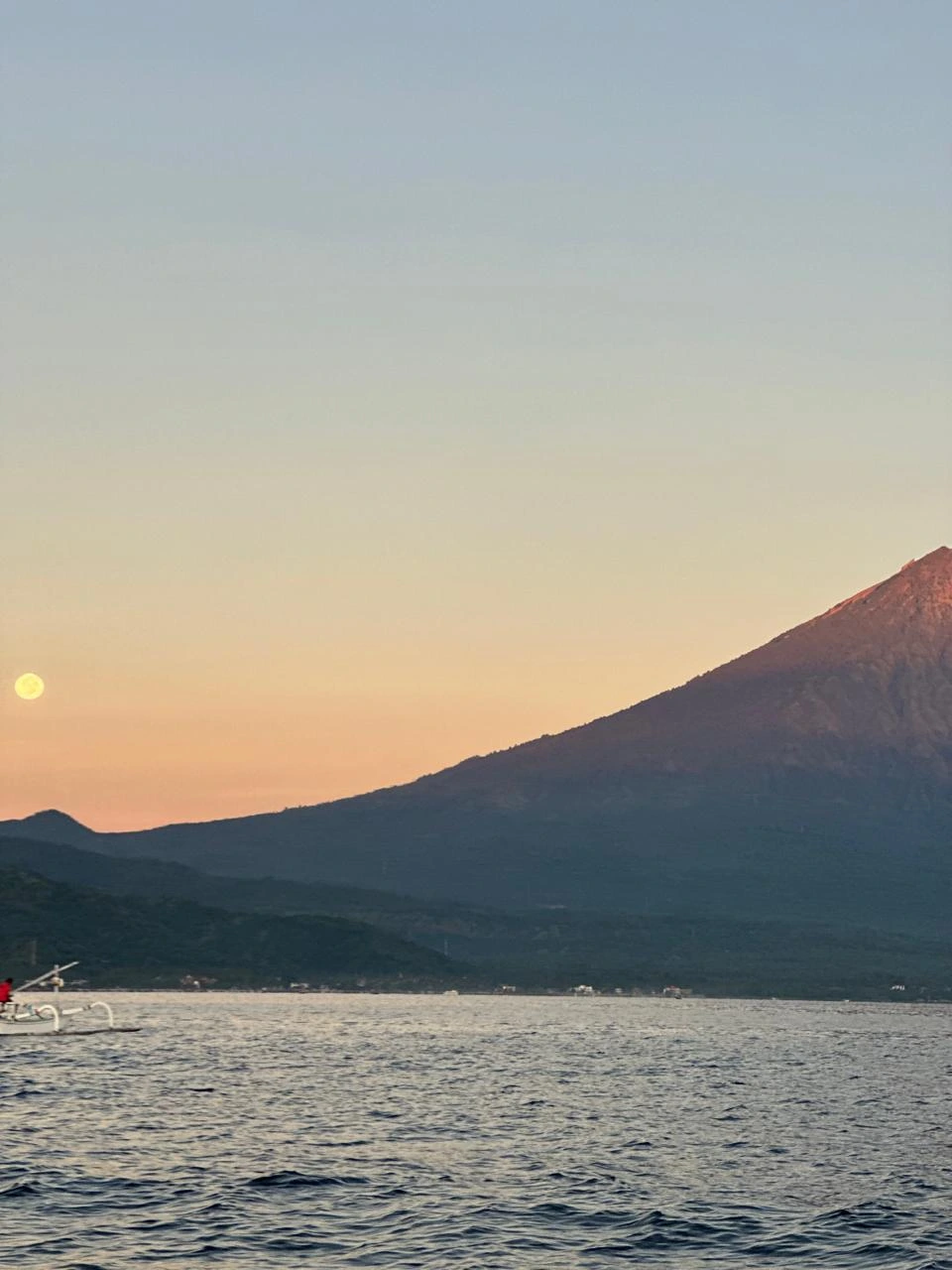 Full moon rising beside Mount Agung at dusk in Amed