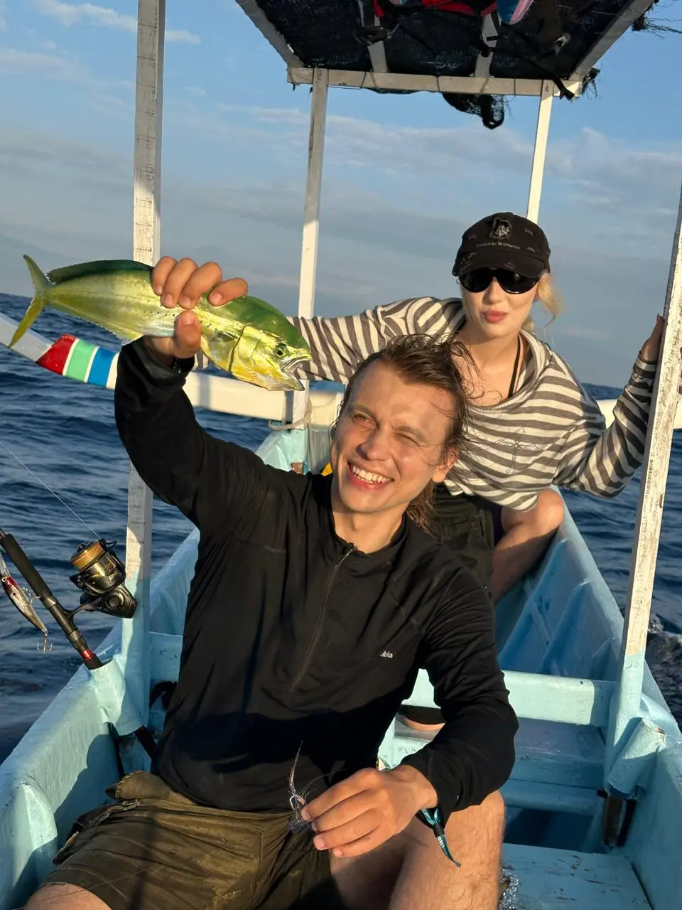 Two anglers on a boat holding freshly caught tuna off Amed