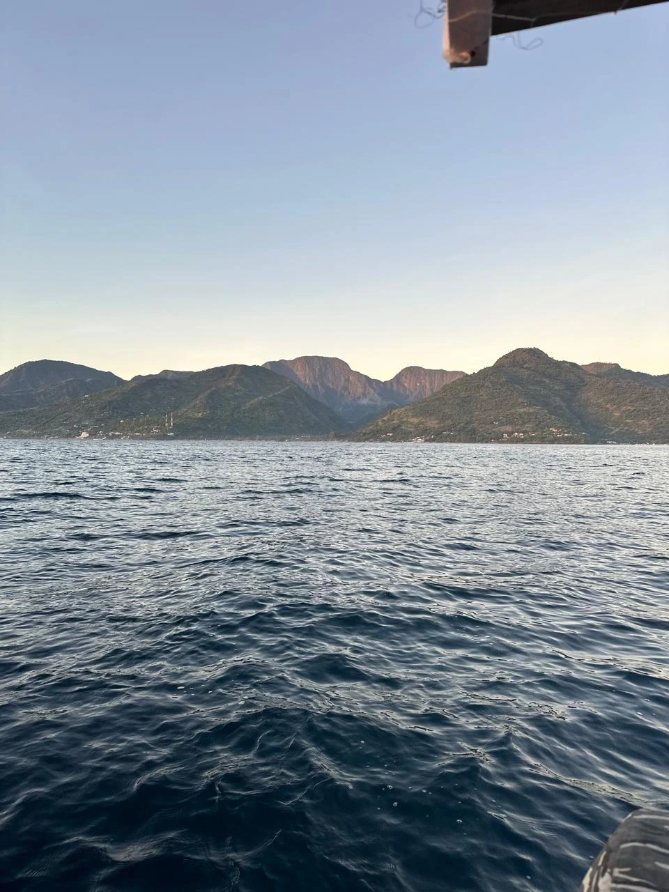 Green coastal hills of Amed seen from a boat at sea