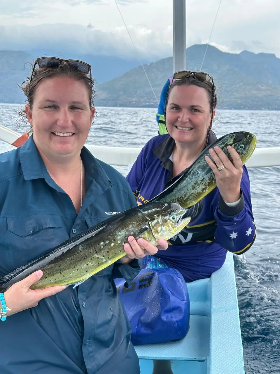 Two women holding mahi-mahi caught on a fishing trip in Amed
