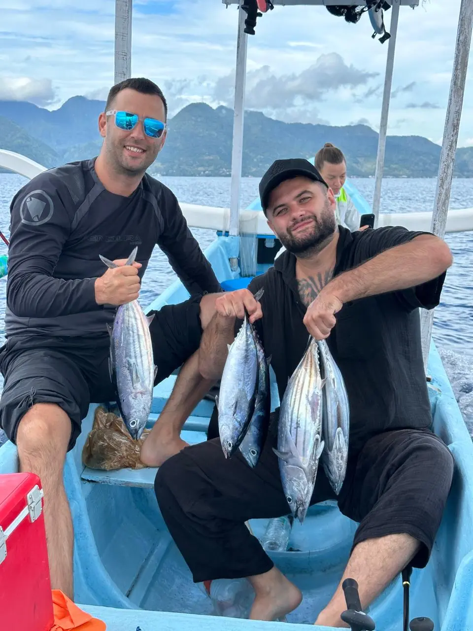 Anglers on a boat holding their freshly caught tuna in Amed